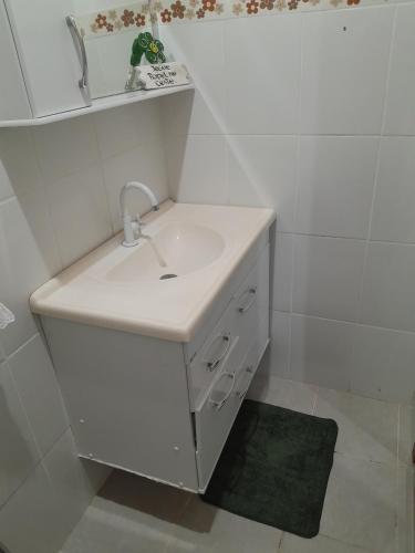 W białej łazience znajduje się umywalka i lustro. w obiekcie Casa da paz w mieście Miguel Pereira