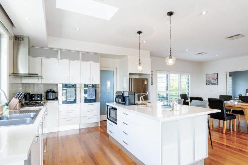 a kitchen with white cabinets and a dining room at Luxurious Comfort with Bay Views in Frankston South