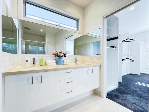 a bathroom with white cabinets and a large mirror at Luxurious Comfort with Bay Views in Frankston South