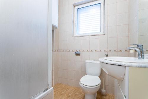 ein Bad mit einem WC, einem Waschbecken und einem Fenster in der Unterkunft Apartments with a parking space Vinisce, Trogir - 1165 in Vinišće
