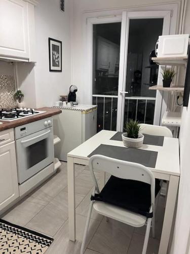uma cozinha com uma mesa branca, uma mesa e cadeiras em Très bel appart à 2mns du Metro et du Canal/Parc em Pantin