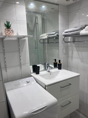 uma casa de banho branca com um lavatório e um espelho em Très bel appart à 2mns du Metro et du Canal/Parc em Pantin