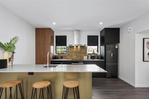 a kitchen with black and white appliances and stools at Simply The Best CBD 3 Mins Plus Garage in Christchurch