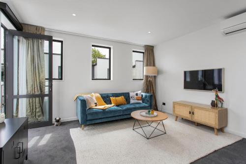 a living room with a blue couch and a table at Simply The Best CBD 3 Mins Plus Garage in Christchurch