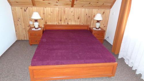 a bedroom with a wooden bed with a purple bedspread at Dom Wakacyjny in Rowy