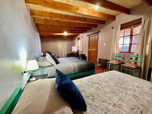 - une chambre avec 2 lits et 2 chaises dans l'établissement casa turis, à San Pedro de Atacama