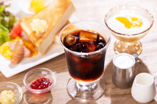 una bebida en un vaso sobre una mesa con un plato de comida en City Hotel Air Port in Prince, en Izumisano