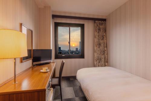 a hotel room with a bed and a desk and a window at City Hotel Air Port in Prince in Izumi-Sano