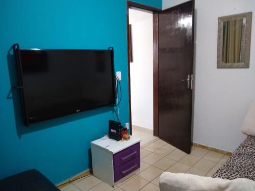 a living room with a flat screen tv on a blue wall at Casa Jardim do Mar - Ubatuba - Praia Grande in Ubatuba