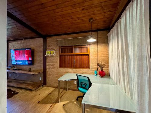 a table and a chair in a room with a television at Pousada Chalés Jardim das Bromélias - Visconde de Mauá in Visconde De Maua