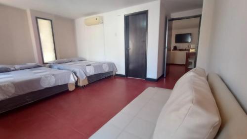 een hotelkamer met 2 bedden en een bank bij Apartamentos Flowers House in Valledupar