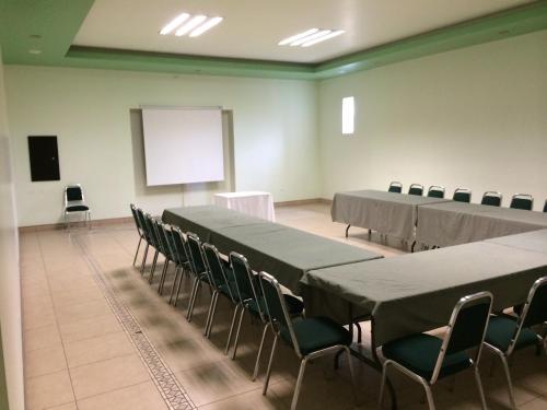 una sala de conferencias con mesas, sillas y una pantalla en Tarahumara Inn, en Cuauhtémoc