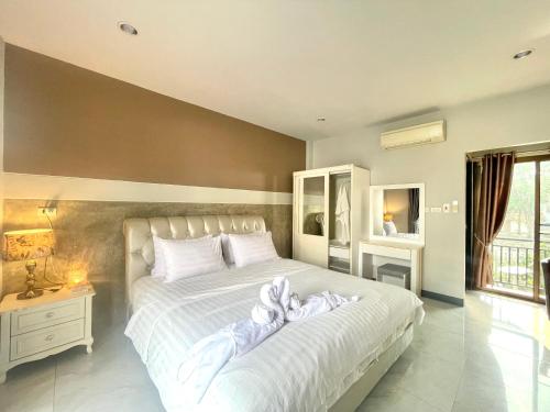 um quarto com uma grande cama branca com toalhas em Smaids Room em Lampang