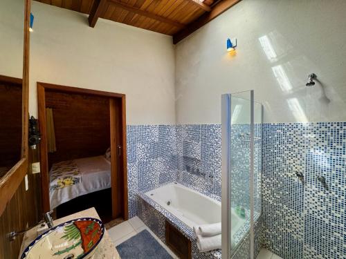 a bathroom with a shower and a tub and a sink at Pousada Chalés Jardim das Bromélias - Visconde de Mauá in Visconde De Maua