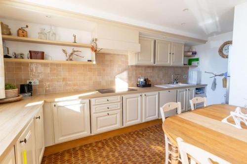 une cuisine avec des armoires blanches et une table en bois dans l'établissement Appartement spacieux avec vue panoramique, à Cassis