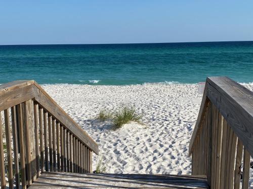 a wooden staircase leading to a beach with the ocean at Your Beach Therapy Awaits at Sans Souci in Pensacola Beach