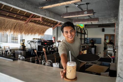 a man standing behind a counter with a drink at El Tropico Boutique Hotel in Kuta Lombok