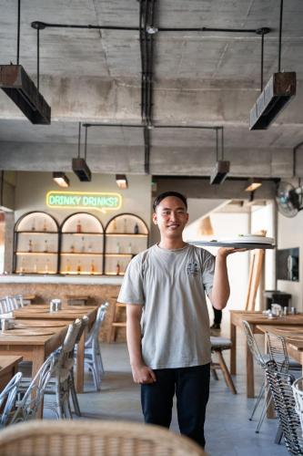 a young man holding a tray in a restaurant at El Tropico Boutique Hotel in Kuta Lombok