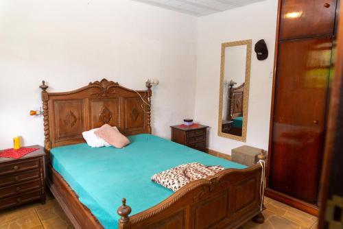 1 dormitorio con cama de madera y espejo en Recanto do majo, en Petrópolis
