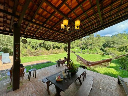 a patio with a table and chairs and a hammock at Pousada Chalés Jardim das Bromélias - Visconde de Mauá in Visconde De Maua