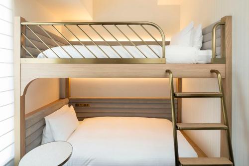 two bunk beds in a small room with a ladder at Hotel Comento Yokohama Kannai in Yokohama