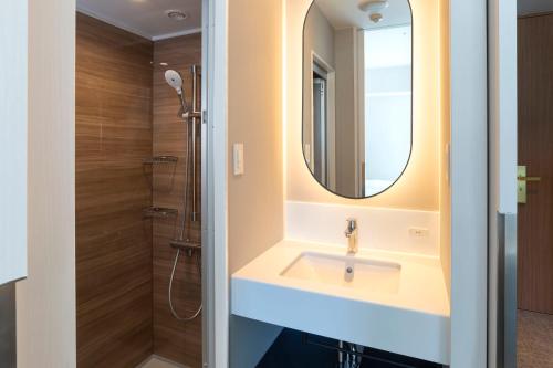 een badkamer met een wastafel en een douche bij Hotel Comento Yokohama Kannai in Yokohama
