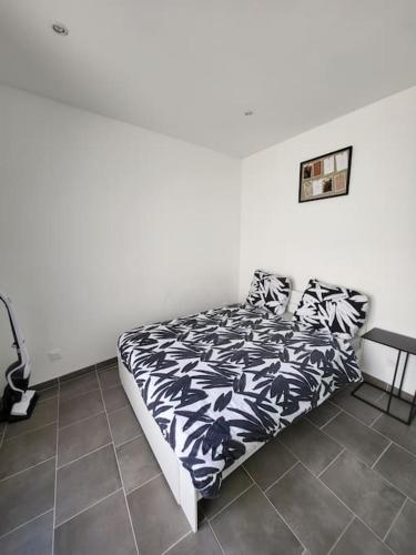 une chambre avec un lit avec une couverture noire et blanche dans l'établissement appartement cosy et chaleureux, à Amiens