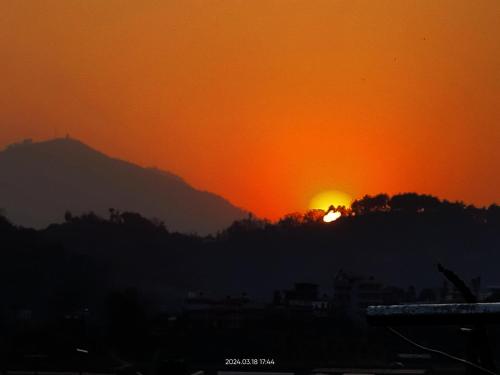 a sunset with the sun setting behind a mountain at COMMUNITY HOLIDAY INN in Panauti