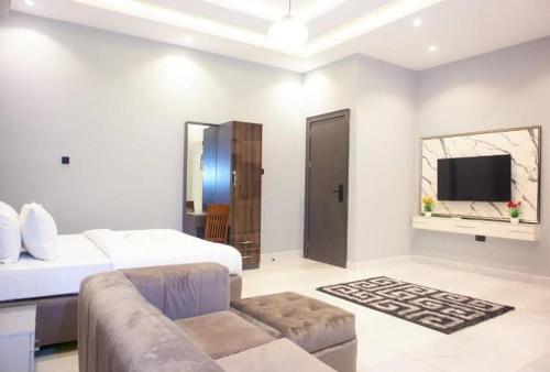 - une chambre avec un lit, un canapé et une télévision dans l'établissement Jovini, à Abuja