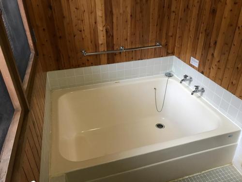 Pension Yamasan في Nakafurano: حوض استحمام أبيض في حمام بجدران خشبية