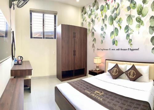 a bedroom with a bed and a wall with leaves at BIG Hotel Huế in Hue