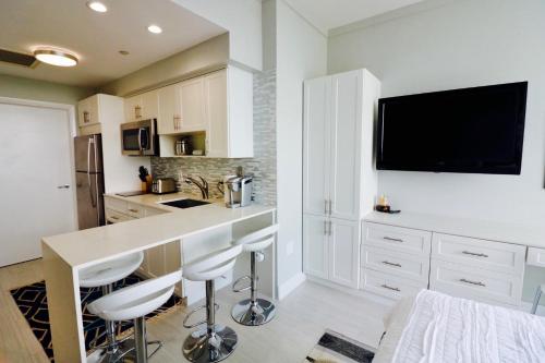 une cuisine avec des armoires blanches et un comptoir avec des tabourets dans l'établissement Coconut Grove 21st Floor Private Studio-Parking & WIFI included, à Miami