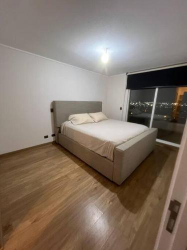 een slaapkamer met een bed en een groot raam bij Apartamento Mirador Lo Campino in Santiago