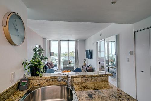 een keuken met een wastafel en een grote klok aan de muur bij Coconut Grove 1 bedroom condo parking included in Miami