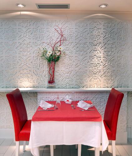 a table with red chairs and a vase with flowers at Garni Hotel Crystal in Kraljevo