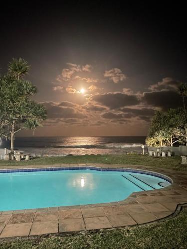 a swimming pool in front of the ocean at night at Beachfront apartment in Ballito! Casablanca in Ballito