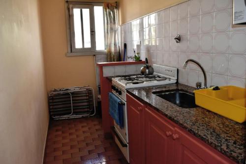 a small kitchen with a stove and a sink at Amplio Depto para 6 con cochera, cerca de Paseo Guemes in Mar del Plata