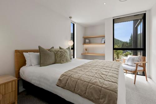 a bedroom with a bed and a chair and a window at Station Bay Lodges - The Retreat in Lake Tekapo