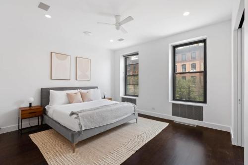 a white bedroom with a bed and two windows at Chelsea Canvas II by RoveTravel Large 3BR Duplex in New York