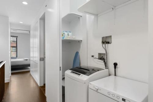a white bathroom with a washing machine and a sink at Chelsea Canvas II by RoveTravel Large 3BR Duplex in New York