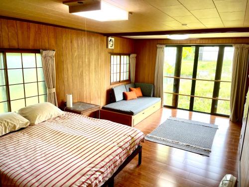 a bedroom with a bed and a bench and windows at Myoko Casa in Myoko