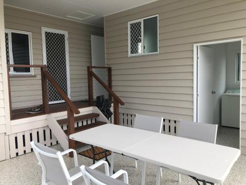 a white table and chairs on the porch of a house at Sandhills Cottage - 3 Meadow Street Keppel Sands in Emu Park