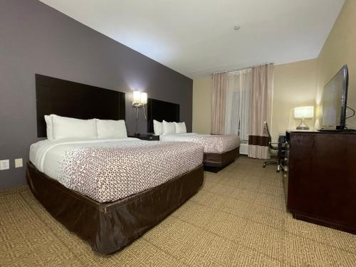 a hotel room with two beds and a television at Spark Suites Hobby Airport in Houston