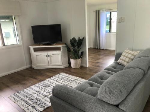 a living room with a couch and a flat screen tv at Sandhills Cottage - 3 Meadow Street Keppel Sands in Emu Park