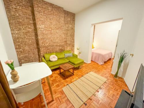 ein Wohnzimmer mit einem grünen Sofa und einer Ziegelwand in der Unterkunft 1727-1RN 1Br with A shared Patio - UES in New York