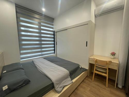 een slaapkamer met een bed, een bureau en een raam bij MinA Home in Xóm Niêm