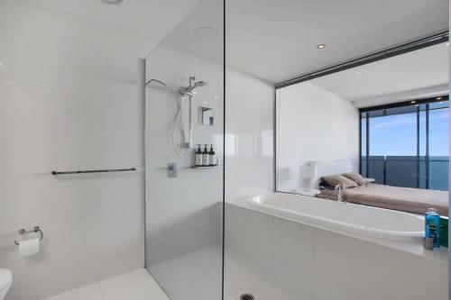 La salle de bains blanche est pourvue d'une douche et d'une baignoire. dans l'établissement NEW! - Circle On Caville 33rd Floor Apartment Ocean Views, à Gold Coast