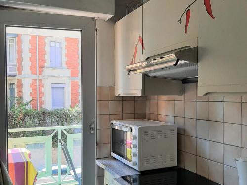 une cuisine avec un four micro-ondes sur un comptoir et une fenêtre dans l'établissement Appartement T3 avec Parking, Proche Centre et Plage - Arcachon - FR-1-319-492, à Arcachon