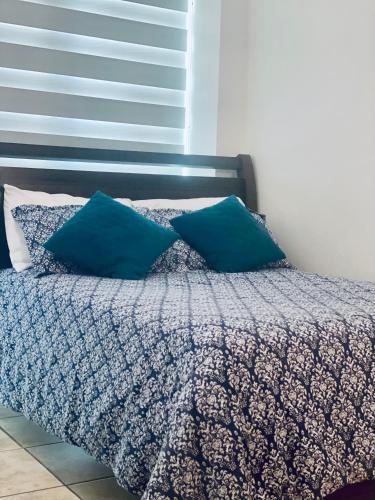 a bed with two blue pillows on top of it at Punta Centinella Yacht Club in Santa Elena