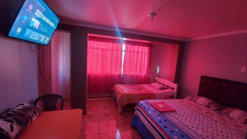 a pink room with two beds and a tv at SOL DEL NORTE in Ayacucho